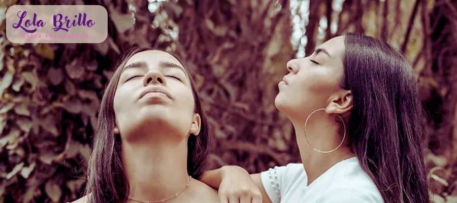 Dos mujeres con los ojos cerrados miran hacia arriba y se sienten empoderadas.
